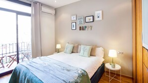 Une chambre à coucher avec un lit, des lampes de chevet, une petite table et un balcon doté d’une balustrade.