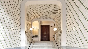Un grand escalier orné d’un mur à motifs et surmonté d’une porte en bois sombre.