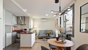 Une cuisine moderne dotée d’un îlot central, un coin repas avec une table ronde et un espace de vie comprenant un canapé et une table basse.
