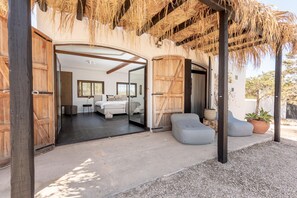 A modern, open-plan bedroom with a large bed, a seating area, and a view of the interior.