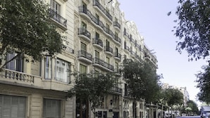 A multi-story building with balconies, parked scooters, and trees along the street. - Rambla Paris Apartment (Barcelona)