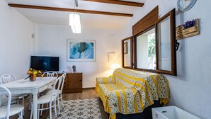 Una stanza piccola e luminosa con un letto, una televisione, un tavolo da pranzo e sedie.