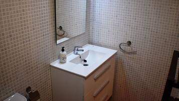 Un baño con un lavabo blanco, un espejo, un perchero para toallas y un inodoro.
