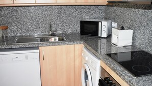 A kitchen with granite countertops, a dishwasher, a washing machine, a microwave, and a stove. - Apartament Sergi in Amposta (Amposta)