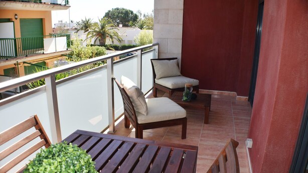 A balcony with wooden furniture, including a table and two chairs, and a potted plant. - Apartament Sergi in Amposta (Amposta)
