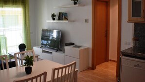 A compact living space with a dining area, a kitchen, and a TV mounted on a cabinet. - Apartament Sergi in Amposta (Amposta)