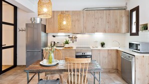 A modern kitchen with wooden cabinets, stainless steel appliances, and hanging pendant lights. - Sant Mori- La Escala Boutique Apartment (Sant Mori)