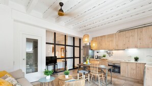 A modern kitchen with wooden cabinets, a dining area with a table and chairs, and a living room with a sofa and a coffee table. - Sant Mori- La Escala Boutique Apartment (Sant Mori)