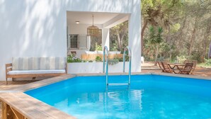 A modern outdoor pool area with a wooden deck, a lounge chair, and a dining set. - Can Vert - Casa Rural Ideal Para Desconectar (Santa Eulalia del Rio)