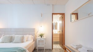 A bedroom with a bed, bedside table with a lamp, a bench with towels, and a mirror on the wall. - Can Vert - Casa Rural Ideal Para Desconectar (Santa Eulalia del Rio)