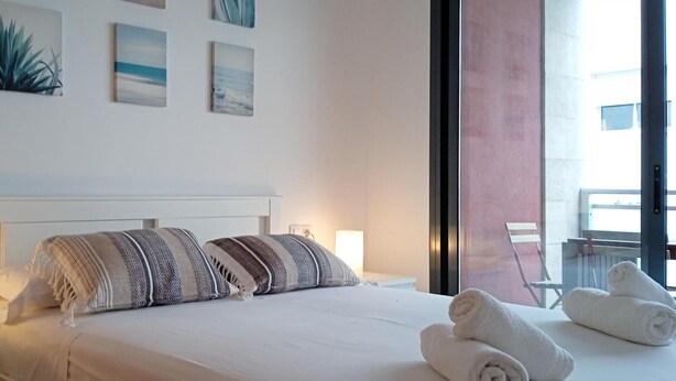 Habitación de hotel con cama, lámparas de noche, vistas al exterior y obras de arte en la pared.