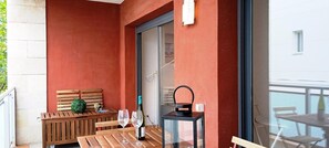 A balcony with a wooden bench, two wine glasses, and a bottle of wine on a table. - Apartament Julia in Amposta (Amposta)