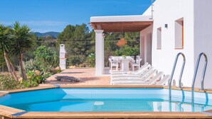 A pool area with lounge chairs and a pergola, surrounded by a garden and a view of the mountains. - Villa Sa Planeta in Sant Josep de Sa Talaia (Sant Josep de sa Talaia)