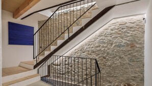 Un escalier avec un mur en pierre, des marches en bois et une rampe en métal.