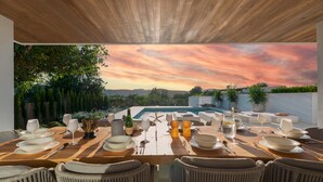 An outdoor dining area with a view of the mountains and a sunset. - Can Palau in Santa Eul ria des Riu (Santa Eulalia del Rio)