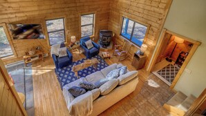 Un interior acogedor de cabaña con un sofá, una mesa de centro y un estufa de leña.