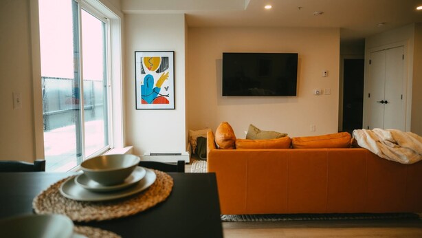 A modern living room with a sofa, a flat-screen TV, and artwork on the wall. - 704 (Halifax)