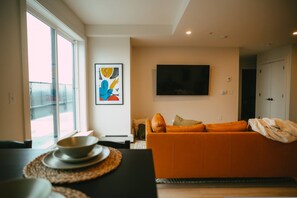 Un salon moderne avec un canapé, un téléviseur à écran plat et des œuvres d’art accrochées au mur.
