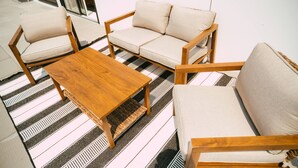 A room with a sofa set, a wooden coffee table, and striped floor mats. - 704 (Halifax)