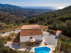 A villa with a tiled roof, a swimming pool, and a patio area with outdoor furniture. - Villa El Retiro in Frigiliana (Torrox)