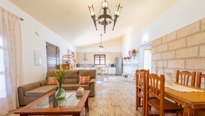 A spacious living room with a sofa, coffee table, and dining area with chairs. - Villa El Retiro in Frigiliana (Torrox)