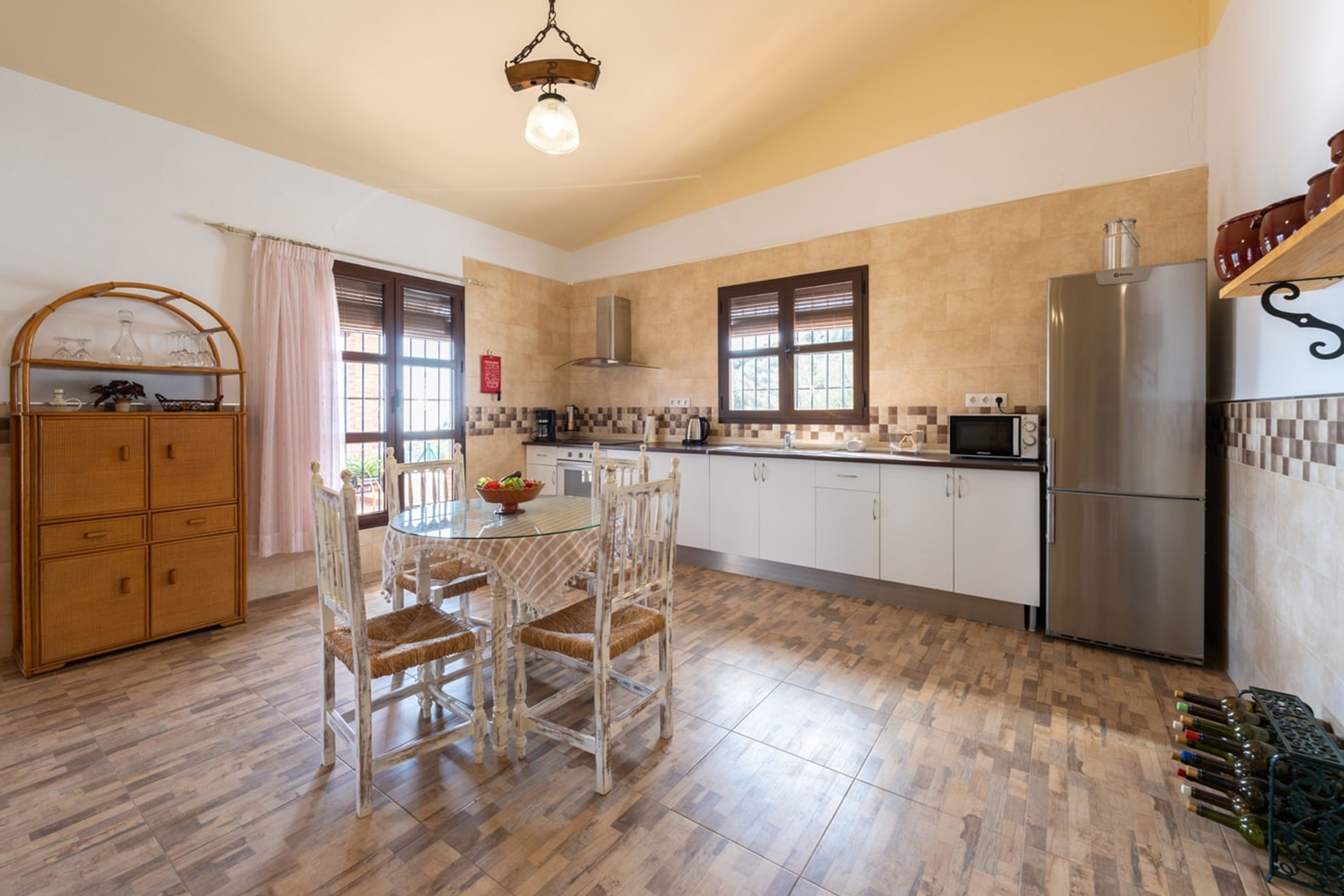 A kitchen with a dining table, chairs, a refrigerator, and a microwave.