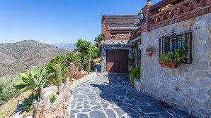 A stone pathway leading to a building with a wooden door and a view of mountains. - Villa Mediterraneo Villa Mediterraneo Solset (Torrox)