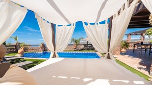 A poolside area with a view of the ocean, white curtains, and outdoor furniture. - Villa Mediterraneo Villa Mediterraneo Solset (Torrox)