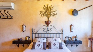 A bedroom with a bed, decorative wall art, a hanging pot, and a wall-mounted clock. - Villa Mediterraneo Villa Mediterraneo Solset (Torrox)