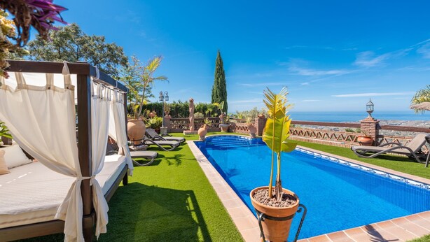 A pool area with a bed and lounge chairs, surrounded by greenery and a clear view of the landscape. - Villa Mediterraneo Villa Mediterraneo Solset (Torrox)