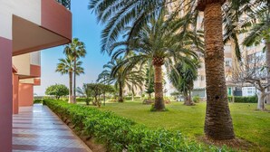 A pathway lined with palm trees and a building with a flat roof. - Apartamento Torrox Playa Solset (Torrox)