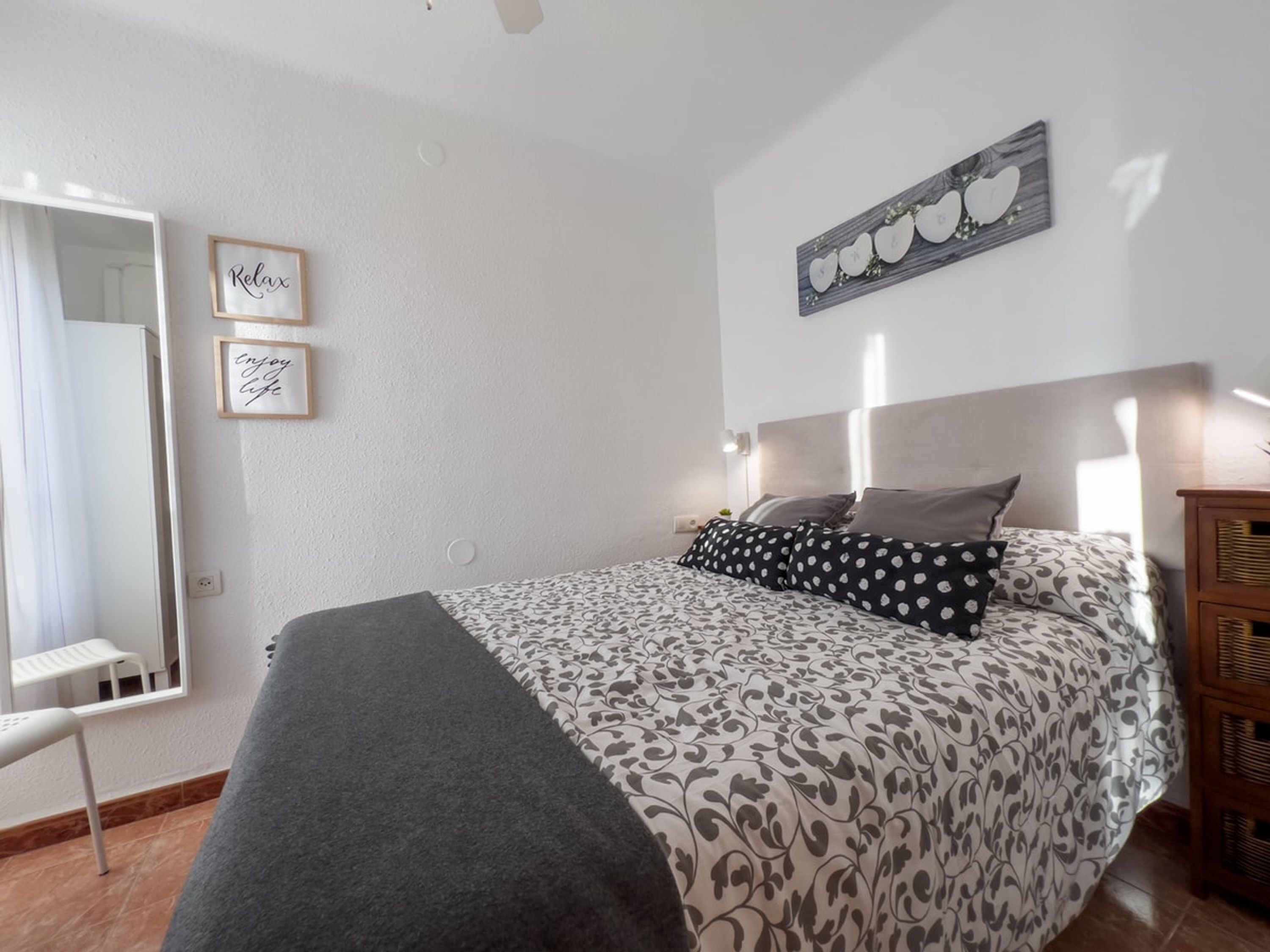 Un dormitorio con cama, espejo y dos citas motivacionales enmarcadas en la pared.