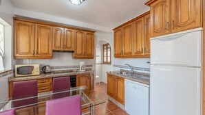 Una cocina con armarios de madera, microondas, cafetera y lavavajillas.