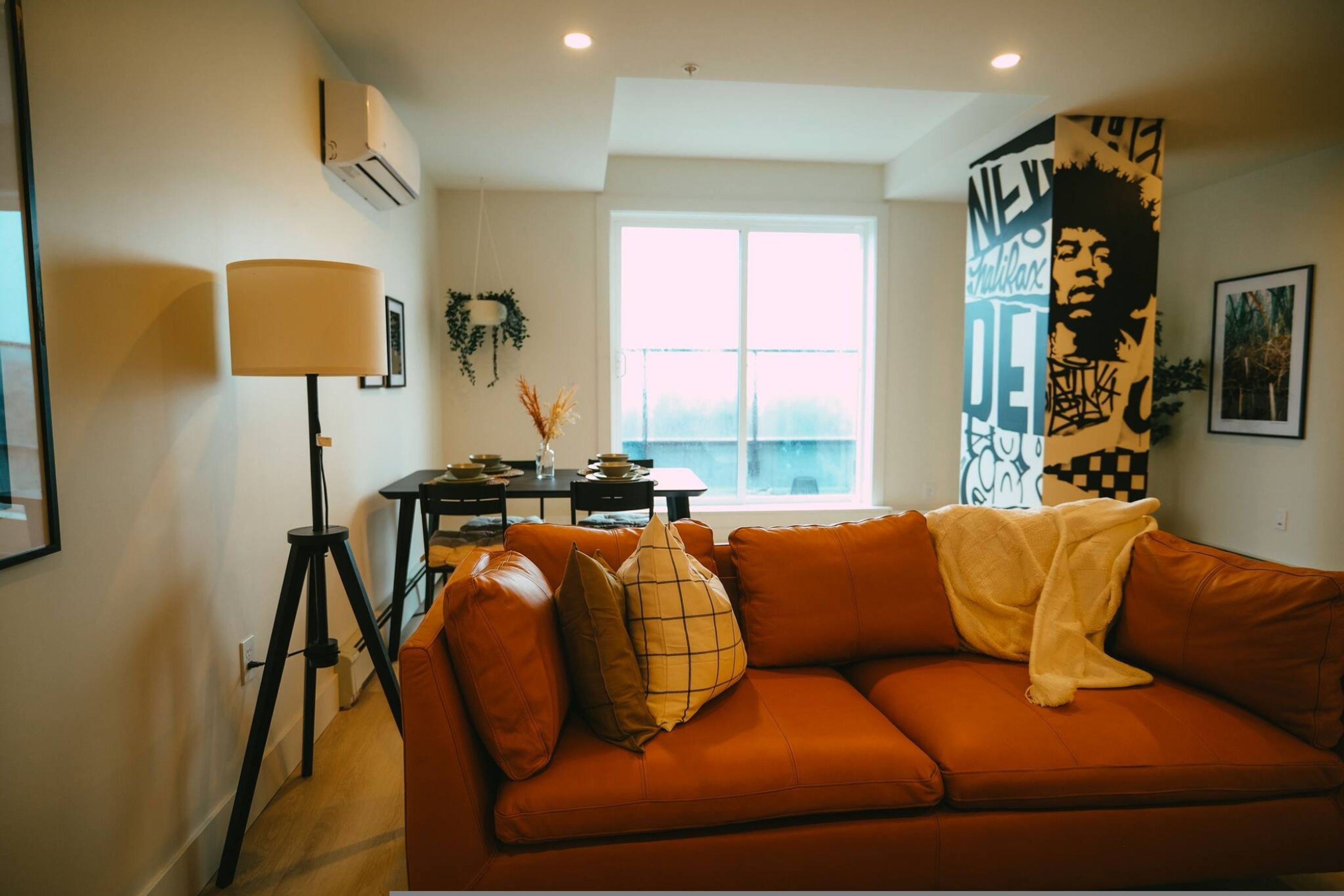 Un salon moderne avec un canapé, une lampe, une table et une fenêtre.