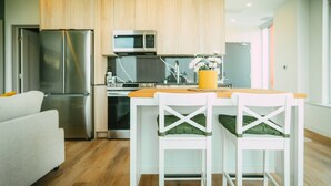 A modern kitchen with wooden cabinets, stainless steel appliances, and a wooden dining table with white chairs. - 903 (Halifax)