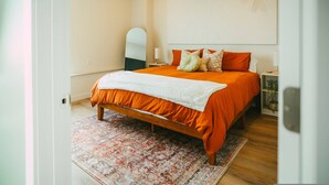 A bedroom with a large bed, a mirror, and a wall art piece. - 903 (Halifax)
