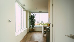 A modern hallway with large windows, a potted plant, and a view of the cityscape. - 903 (Halifax)