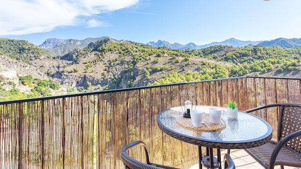 A balcony with a round table and chairs, overlooking a mountainous landscape. - Apartamento Alberti Solset (Frigiliana)