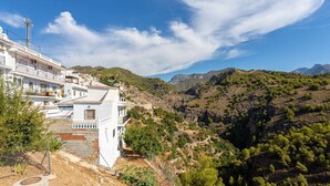A white building with balconies, set against a mountainous backdrop. - Apartamento Alberti Solset (Frigiliana)