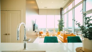 A modern kitchen with a sink and a large window overlooking a living area with a sofa and a plant. - 902 (Halifax)