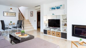 A modern living room with a sofa, coffee table, TV, and a staircase.