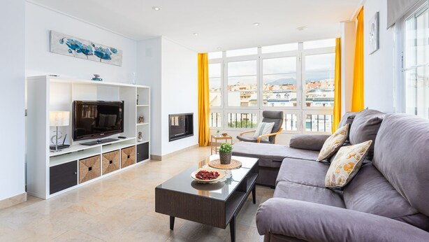 A modern living room with a sofa, TV, and entertainment unit.