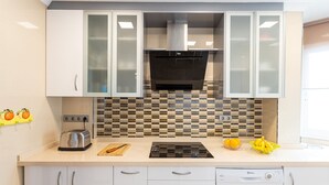 A kitchen with white cabinets, a black stove, and a tiled backsplash.