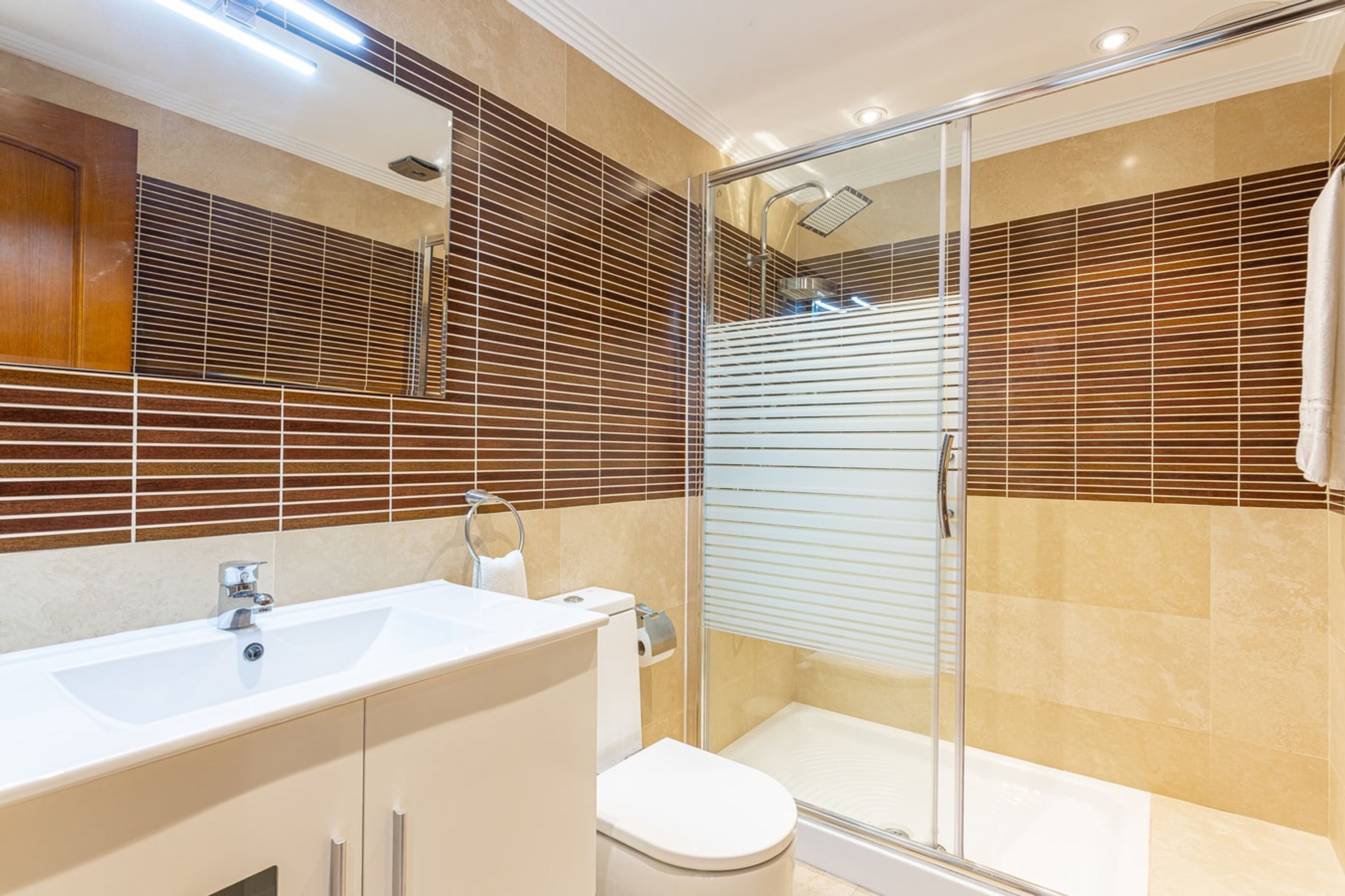 Une salle de bain moderne avec une douche à parois de verre, un lavabo blanc et des toilettes.