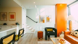 A modern living room with a sofa, a coffee table, and a dining area with chairs and a table. - Ph-2e (Halifax)