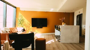 A modern living room with a sofa, ottoman, and a flat-screen TV mounted on the wall. - Ph-2e (Halifax)