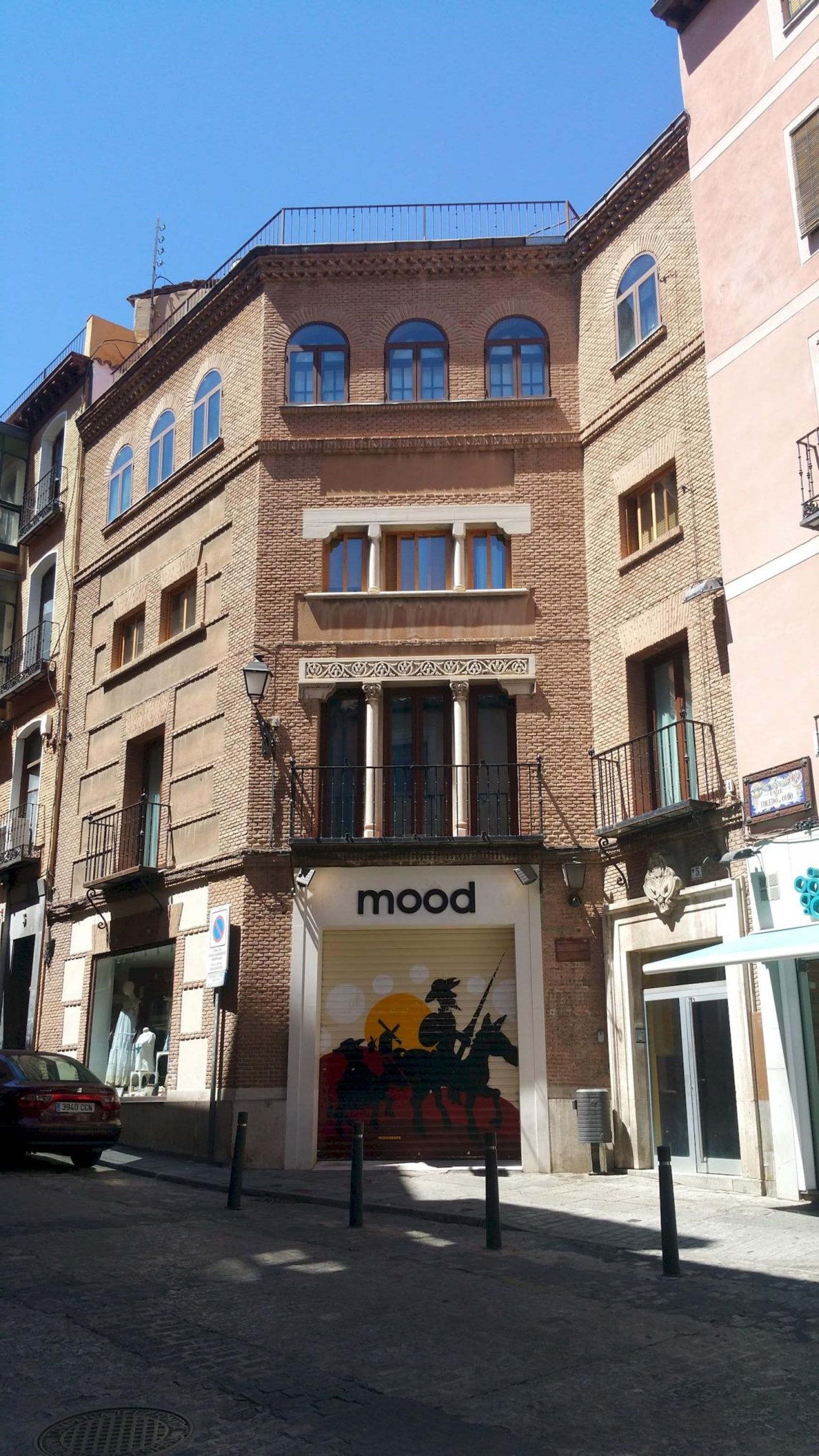 A building with a storefront labeled 'mood' featuring a mural of a historical scene.