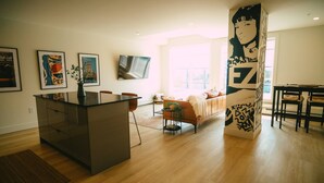 A modern living space with a kitchen island, a sofa, a dining area, and artwork on the walls. - 701 (Halifax)