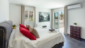 Un dormitorio con una cama grande, un sofá, un armario pequeño y una ventana con vistas al exterior.