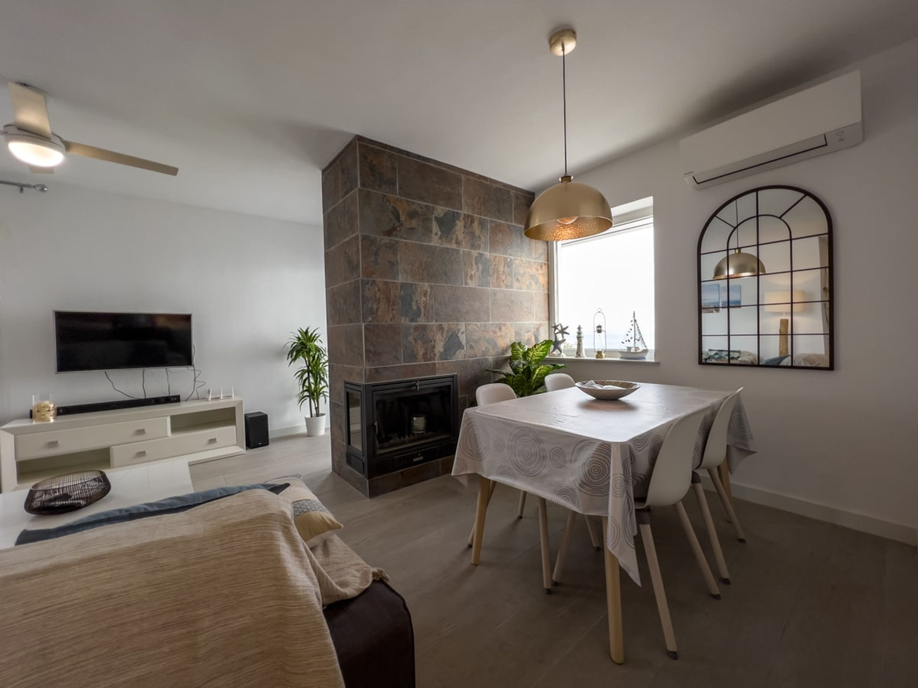 A modern living room with a fireplace, dining table, and a TV mounted on the wall.